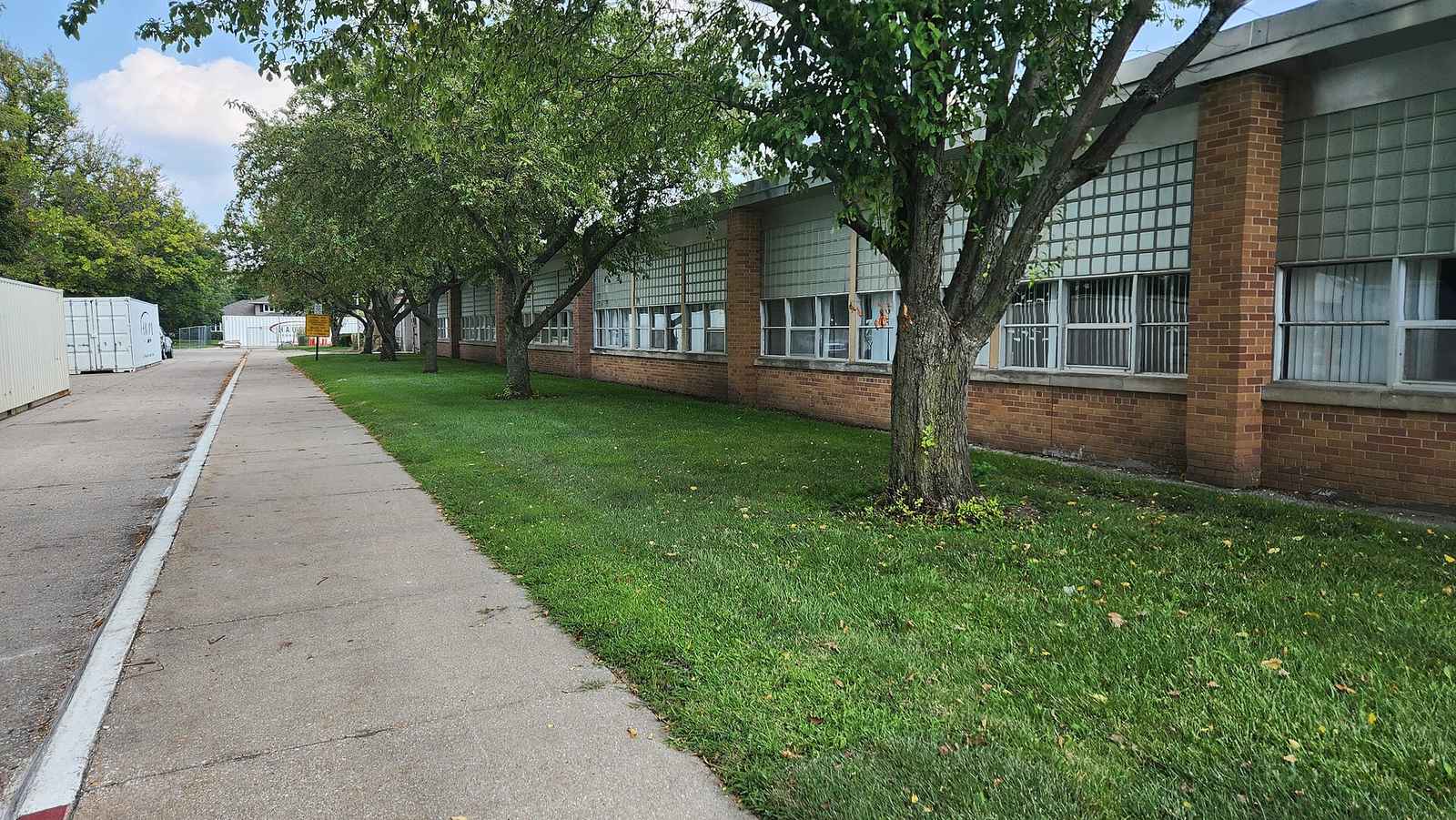 A single-storey elementary school building with trees along the path